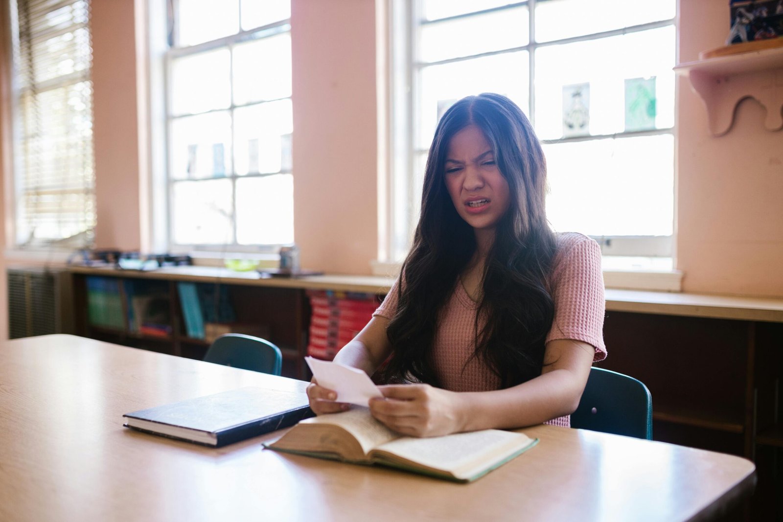 A frustrated woman sitting near a table full of diet books and empty plates.