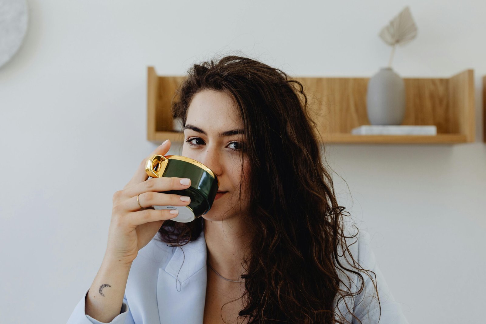 Jessica smiling holding yoga mat and herbal tea cup