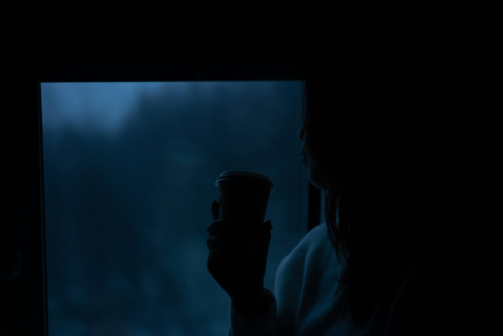 Person holding a cup of warm water mixed with triphala powder at night
