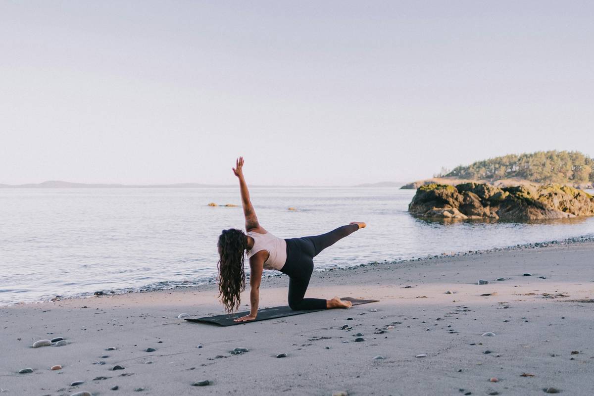A woman practicing yoga outdoors surrounded by nature