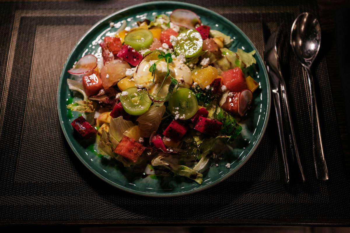 A colorful bowl of roasted chickpeas, carrots, and greens drizzled with tahini dressing