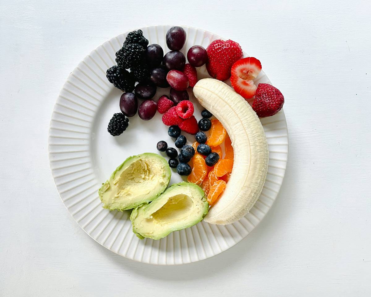 A person practicing mindful eating at a wooden table with fresh food.