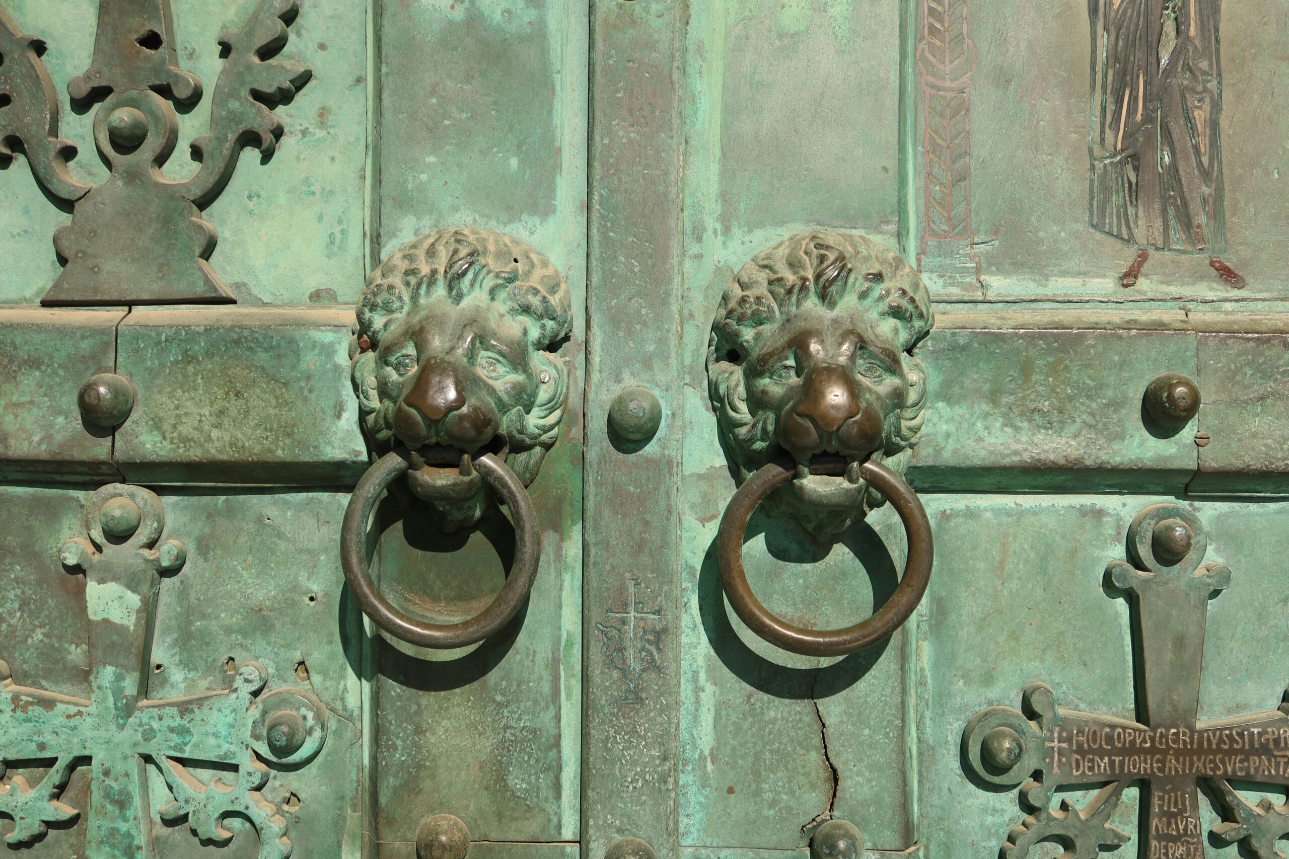 Lion-shaped door knockers adorn a weathered green door.